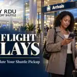 RDU flight delays banner showing a traveler checking her phone beside luggage, with a shuttle van outside airport arrivals.